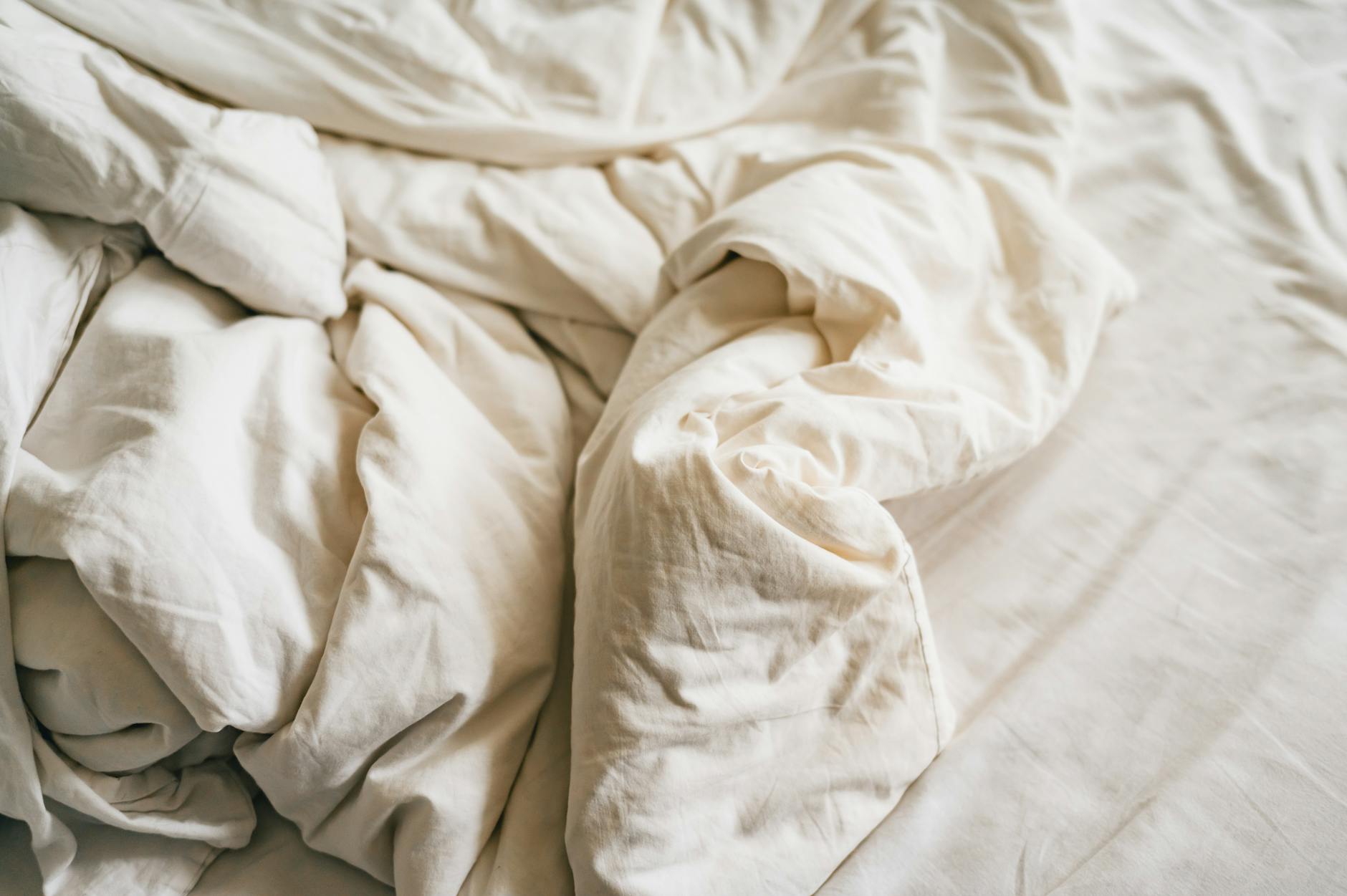 Zbliżenie na pomiętą białą lnianą pościel na łóżku