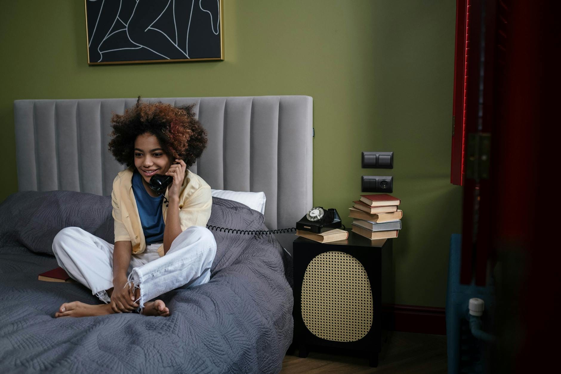 Nastolatka z afro rozmawia przez retro telefon w nowoczesnej sypialni